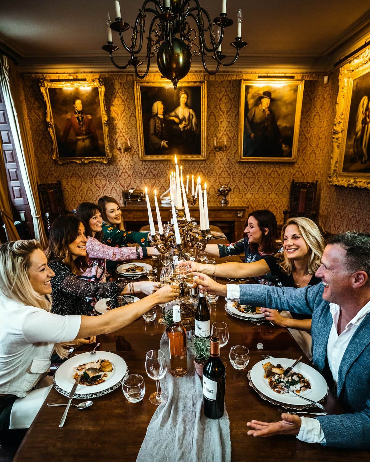 Friends of all ages raising a toast over dinner by candlelight